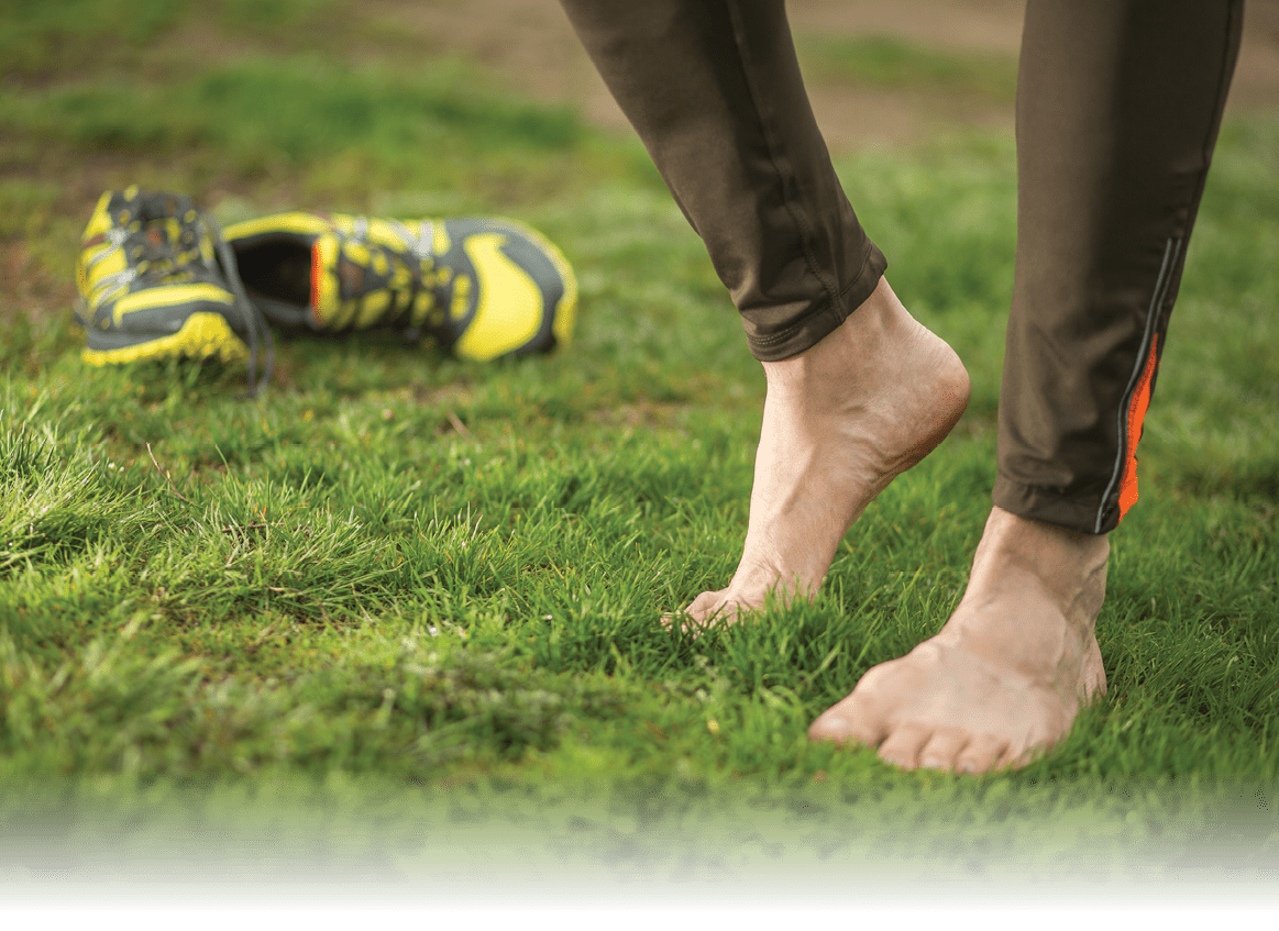 Male runner relaxing after outdoor jogging, workout in spring park. focus on right foot