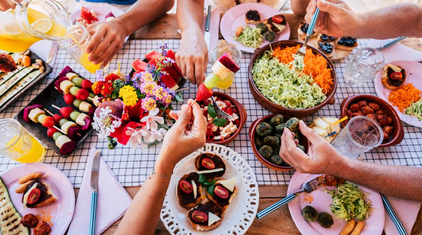 Group of mixed ages generations eating and celebrating together in friendship - family people caucasian concept in close up view of table full of food